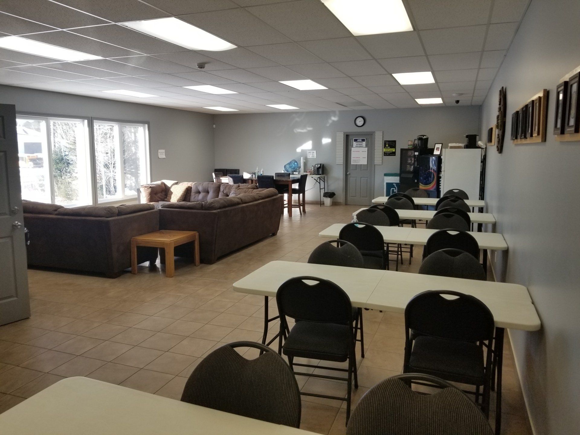 Une pièce intérieure avec tables et chaises, un coin salon avec canapés et une porte.