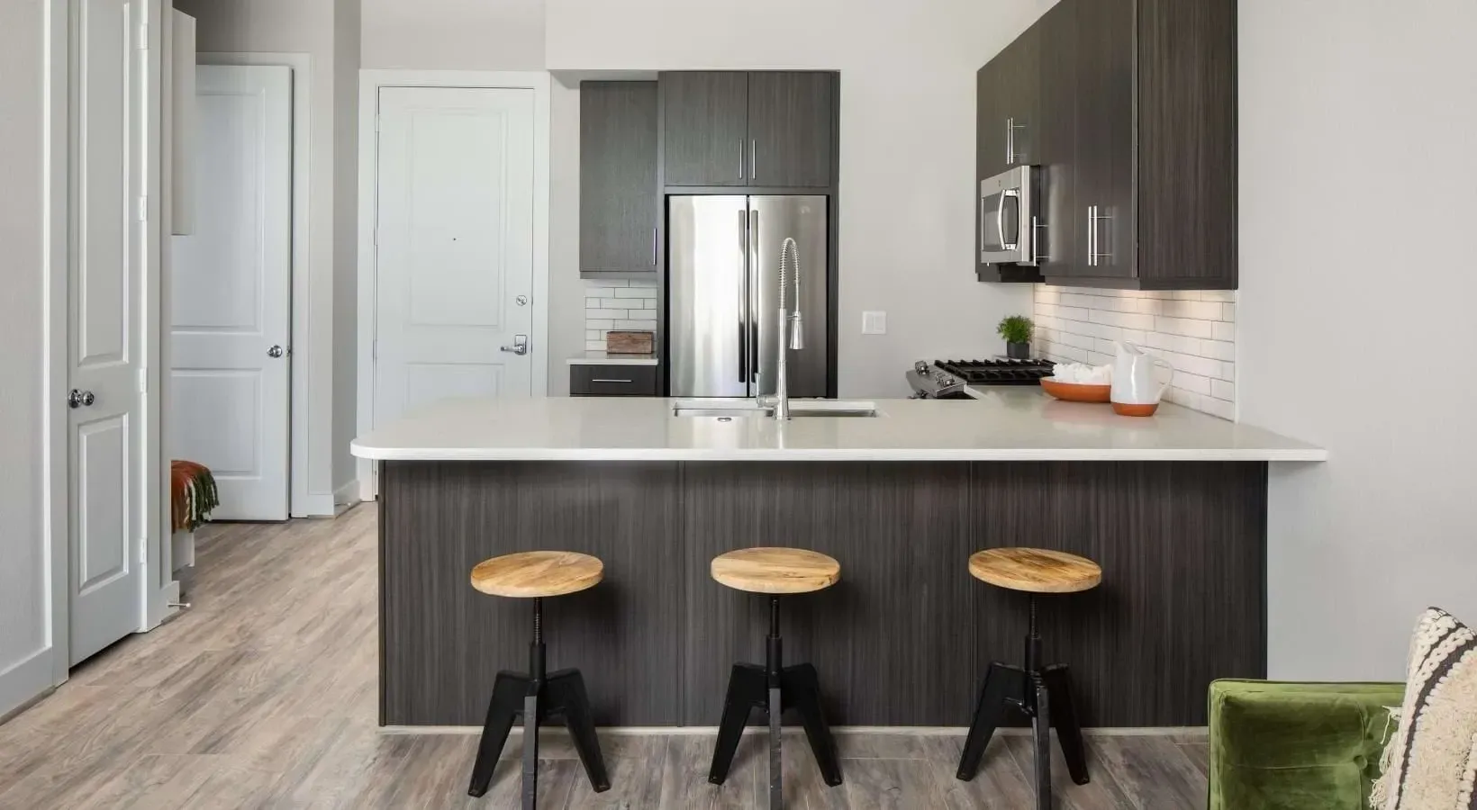 Modern kitchen with dark wood cabinets, stainless steel appliances, and a large island with bar stools.
