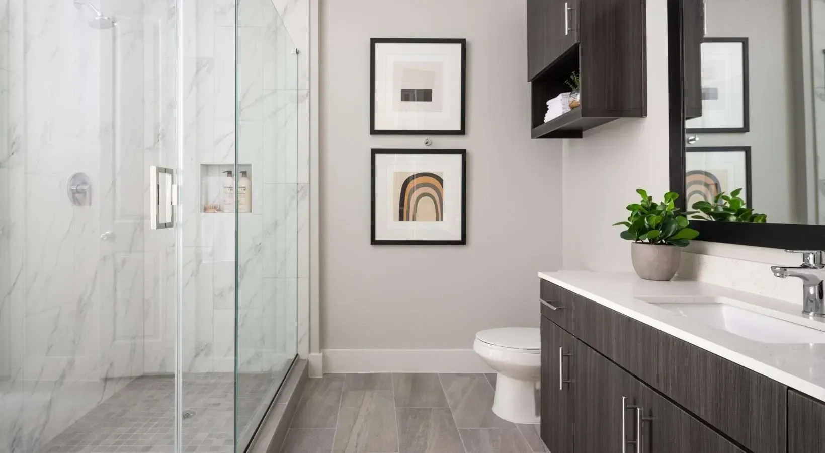 Modern bathroom with a glass-enclosed shower, vanity with sink, and toilet.