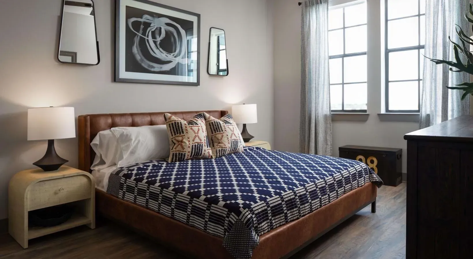 Modern bedroom with a leather headboard bed, decorative pillows, and bedside tables.