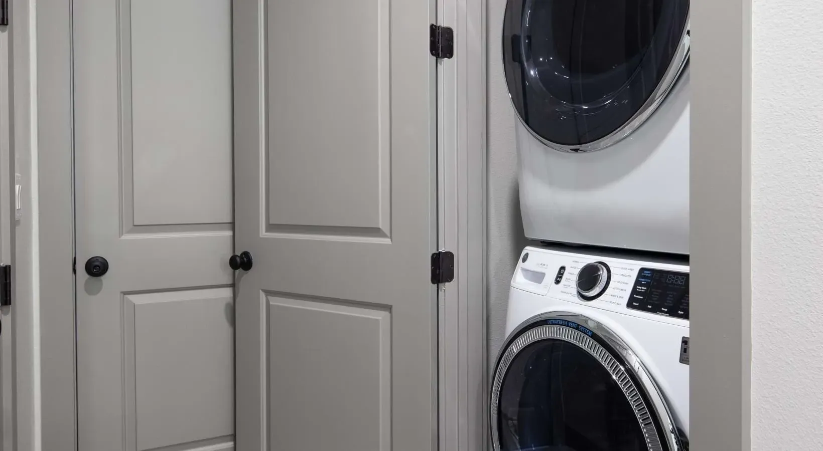 Stacked washer and dryer in a closet with bi-fold doors.
