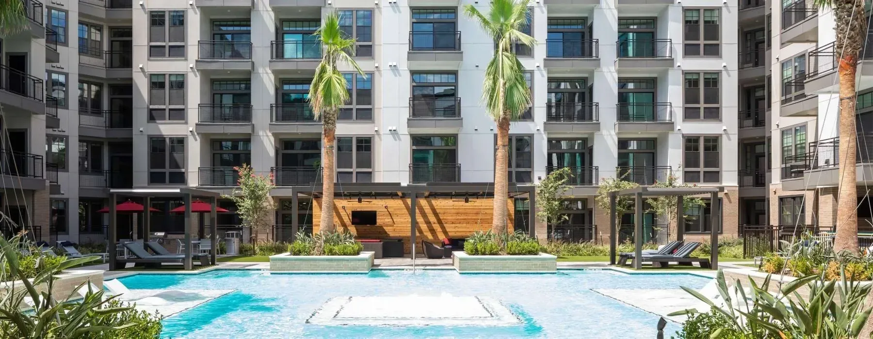 Modern apartment courtyard with blue pool, fountain, and landscaped seating area