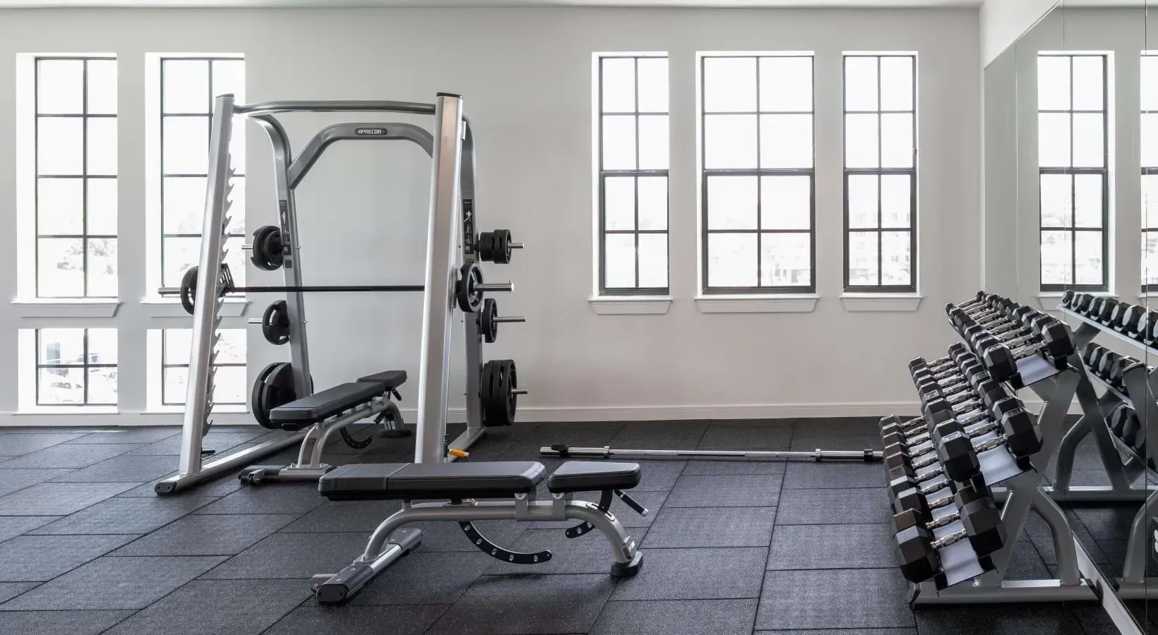 Gym with weightlifting equipment, dumbbells, and workout benches.