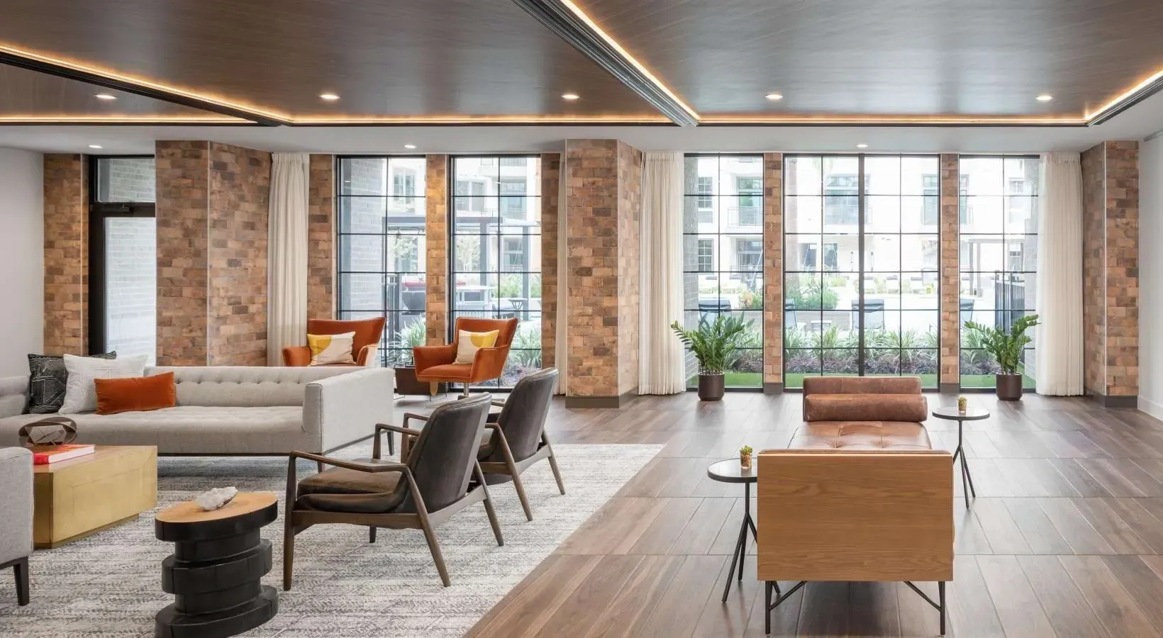 Modern lounge area with seating and large windows overlooking an outdoor space.