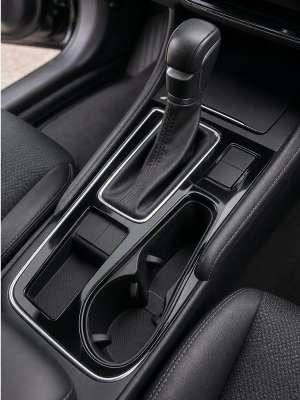 Car center console with automatic gear shifter, cup holder, and storage tray in black trim