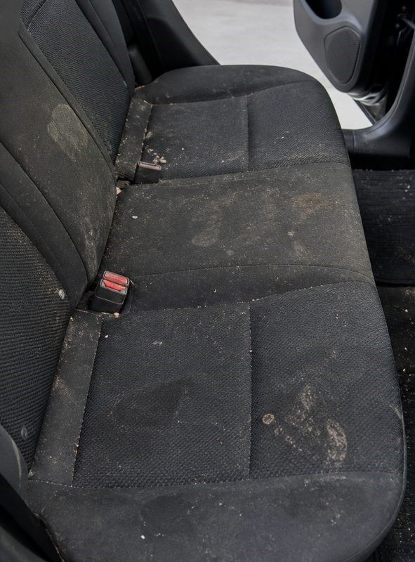 Dirty black car back seat with stains and worn fabric