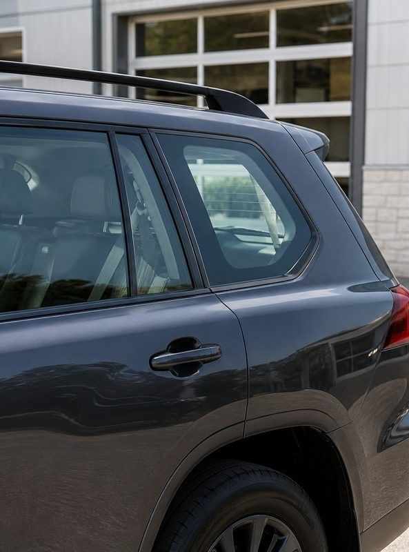 Dark SUV parked outside a building, showing the rear side window and door.