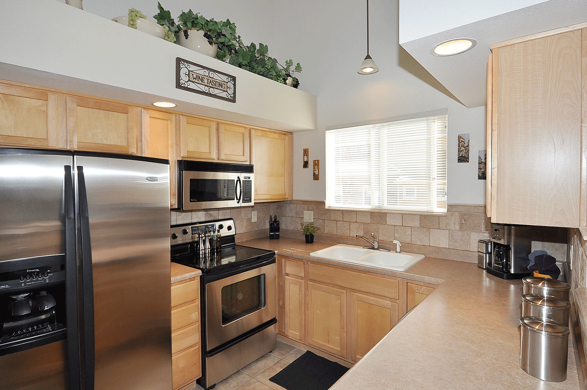 Bright kitchen with stainless steel appliances, light wood cabinets, and a window over the sink