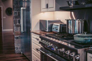 Modern kitchen with stainless steel stove, microwave, pots, and a refrigerator in the background