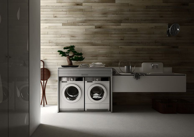 Modern bathroom with twin washing machines under a wooden countertop and a wall-mounted sink