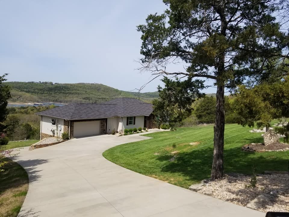 A house with a driveway and a view of a hillside on a sunny day.