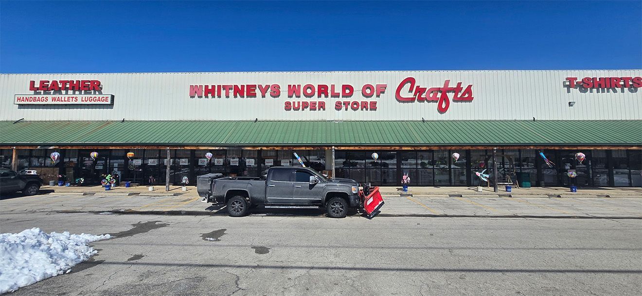 Exterior of Rhinney's World of Crafts Super Store with a truck parked in front. Blue sky overhead.