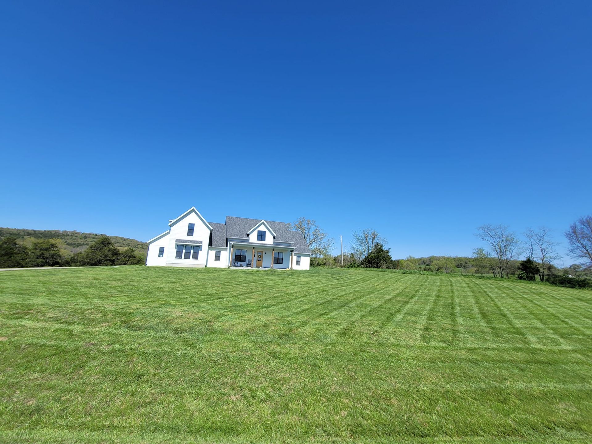 White house on a grassy hill with a blue sky overhead.