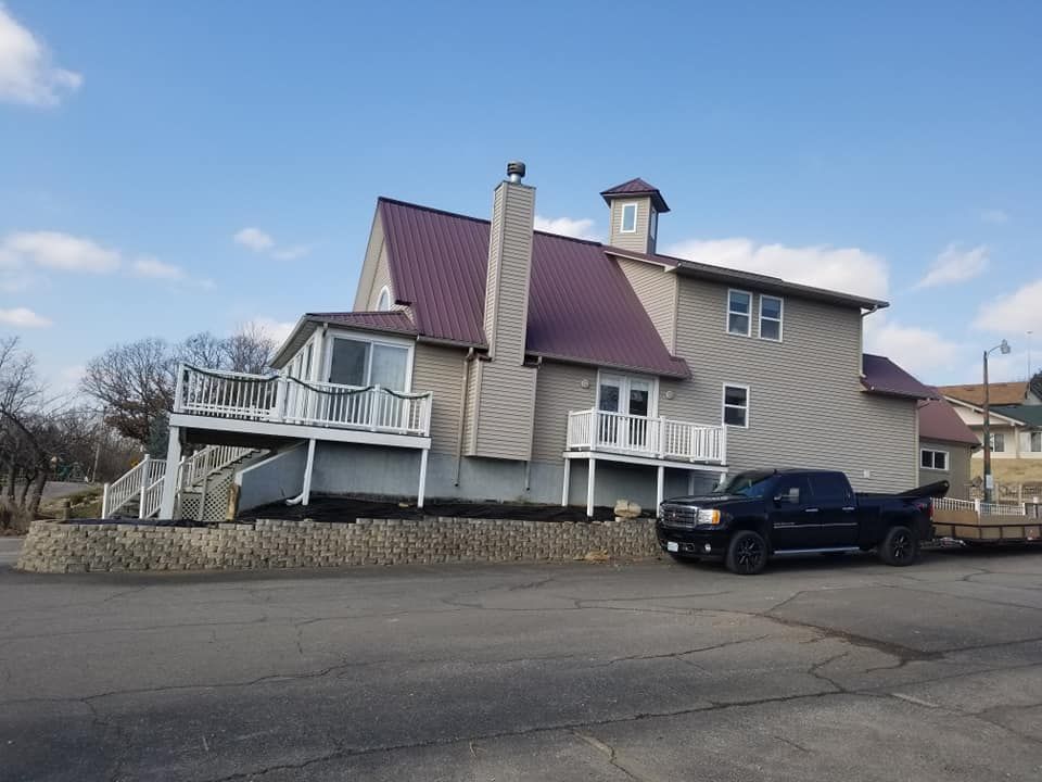 Beige house with a purple roof and a black truck parked outside.