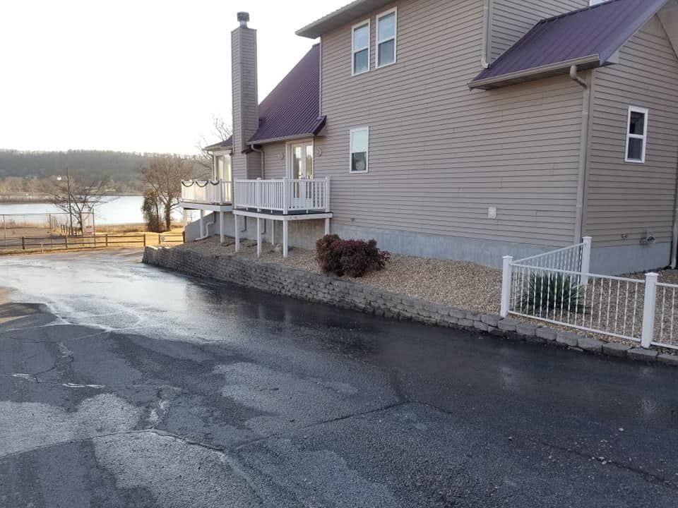 House with a purple roof next to a lake, with a paved driveway in the foreground.