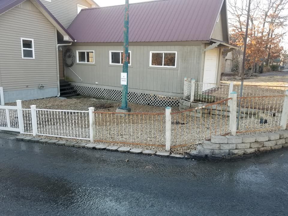 Building exterior with a fence, a brown metal roof, and a gravel yard.