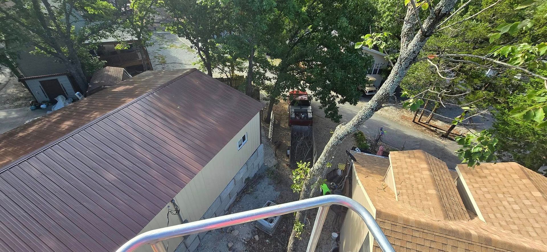 Aerial view of buildings with brown roofs, trees, and a silver railing.