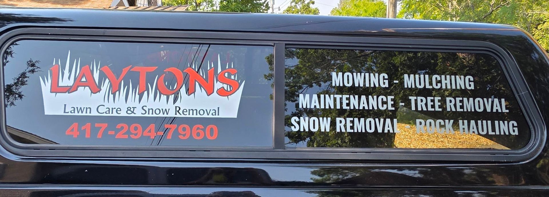 Black truck window with white and red lettering, advertising 