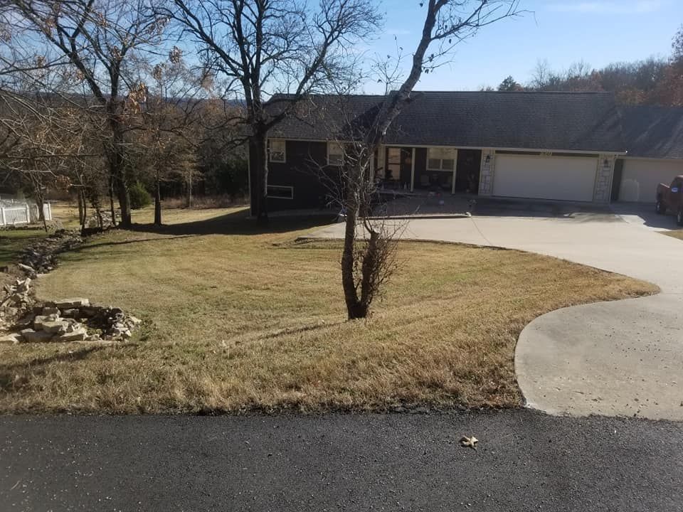 A house with a driveway and brown lawn on a sunny day.