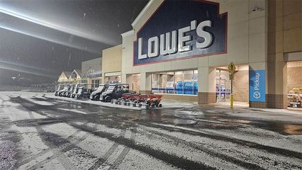 Lowe's store in snowy weather. Snow falling on the parking lot and store front with the Lowe's logo.
