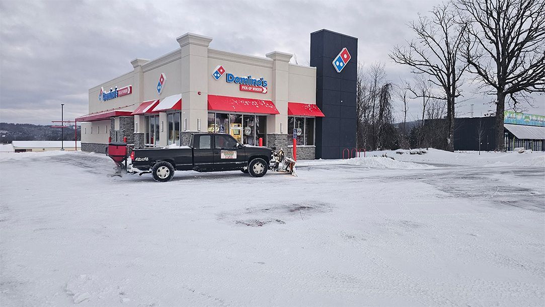 A Domino's Pizza building in a snowy landscape; a black truck is parked in front.