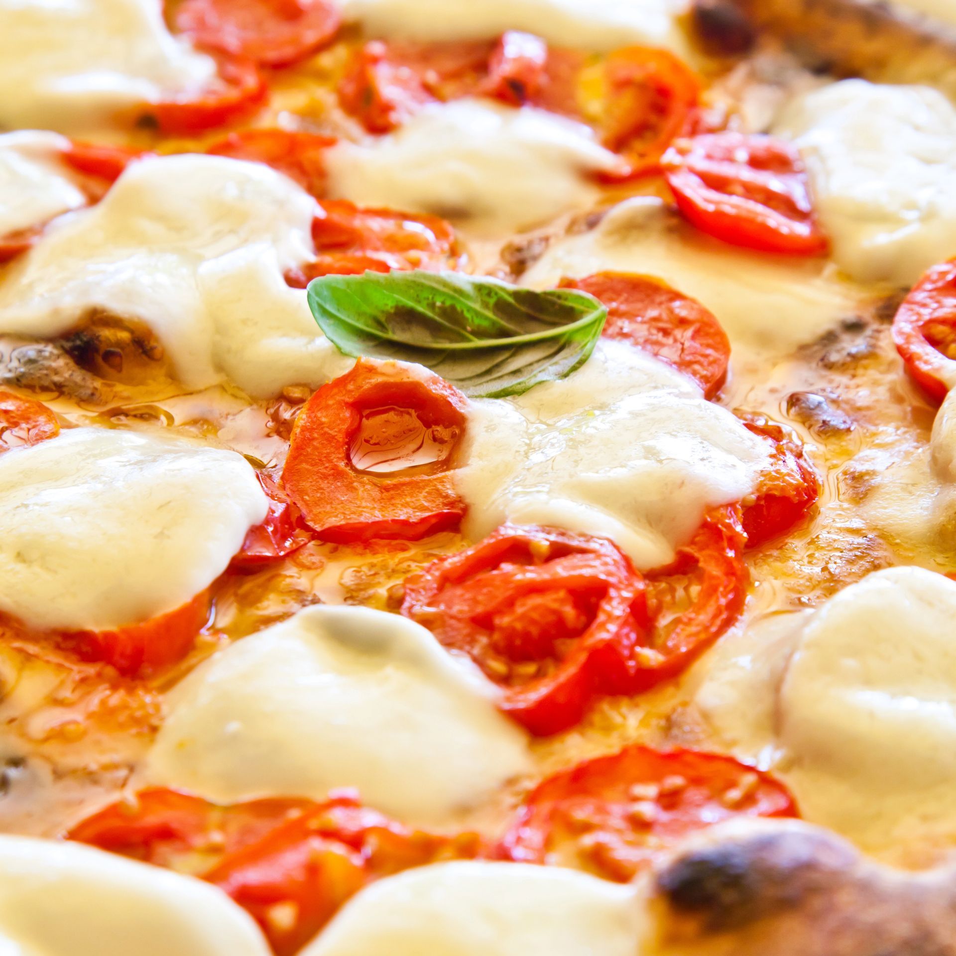 Pizza margherita con mozzarella, fette di pomodoro e basilico.