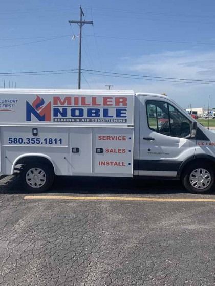 Miller Noble service van parked on a street, with blue and red company branding and phone number.