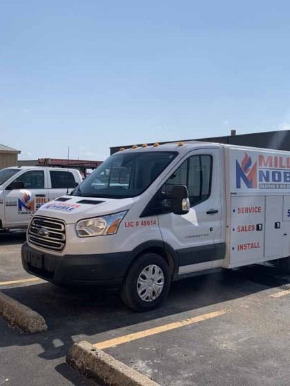 White utility van parked in a lot under a clear blue sky, with company logo on the side.