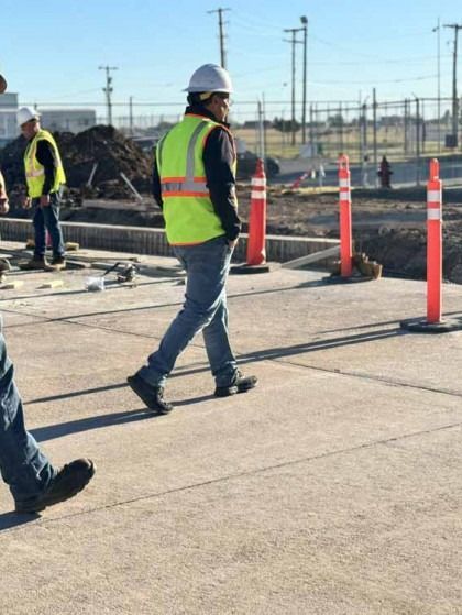 Construction worker in a safety vest walking through a roadwork zone with orange cones and barriers