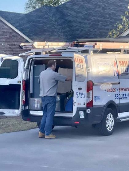 Man loading a white utility van with tools in a suburban driveway at a house