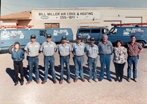 Ten people in front of a Bill Miller Air Cond. & Heating service truck and building