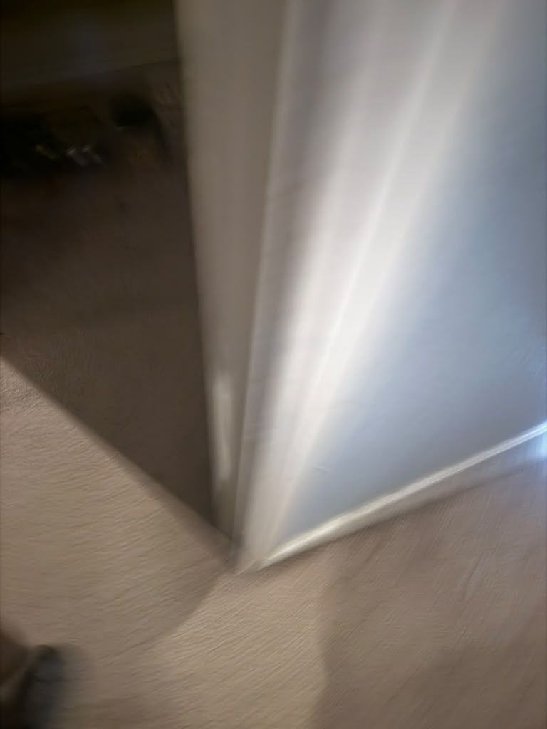 Blurry view of a white door frame meeting beige carpeted floor in an indoor hallway
