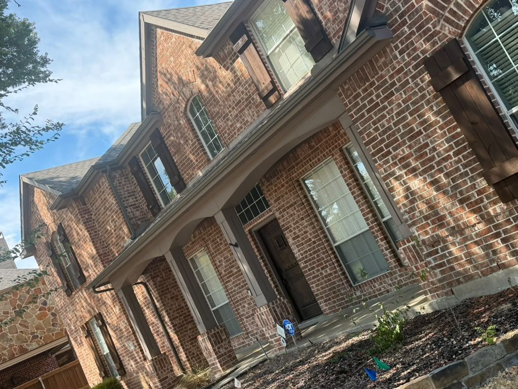 Brick apartment building with white trim and covered entryways on a sunny day