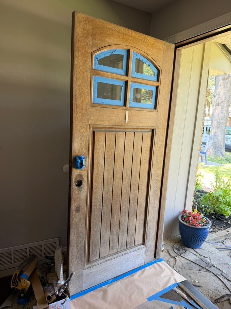 Open wooden front door with blue-trimmed windows, viewed from inside entryway.