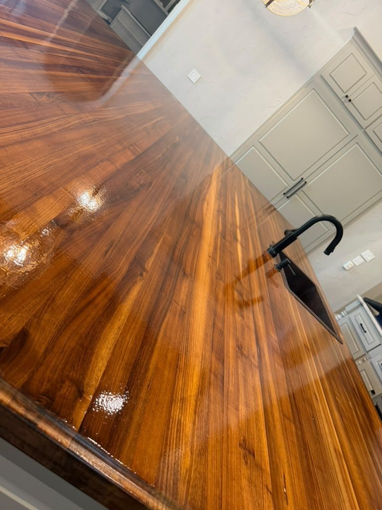 Empty polished wood kitchen island with black faucet and gray cabinets in the background