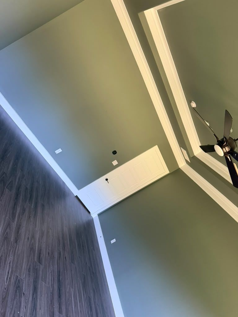 Rotated view of a room ceiling with recessed lights, green walls, and a hanging ceiling fan.