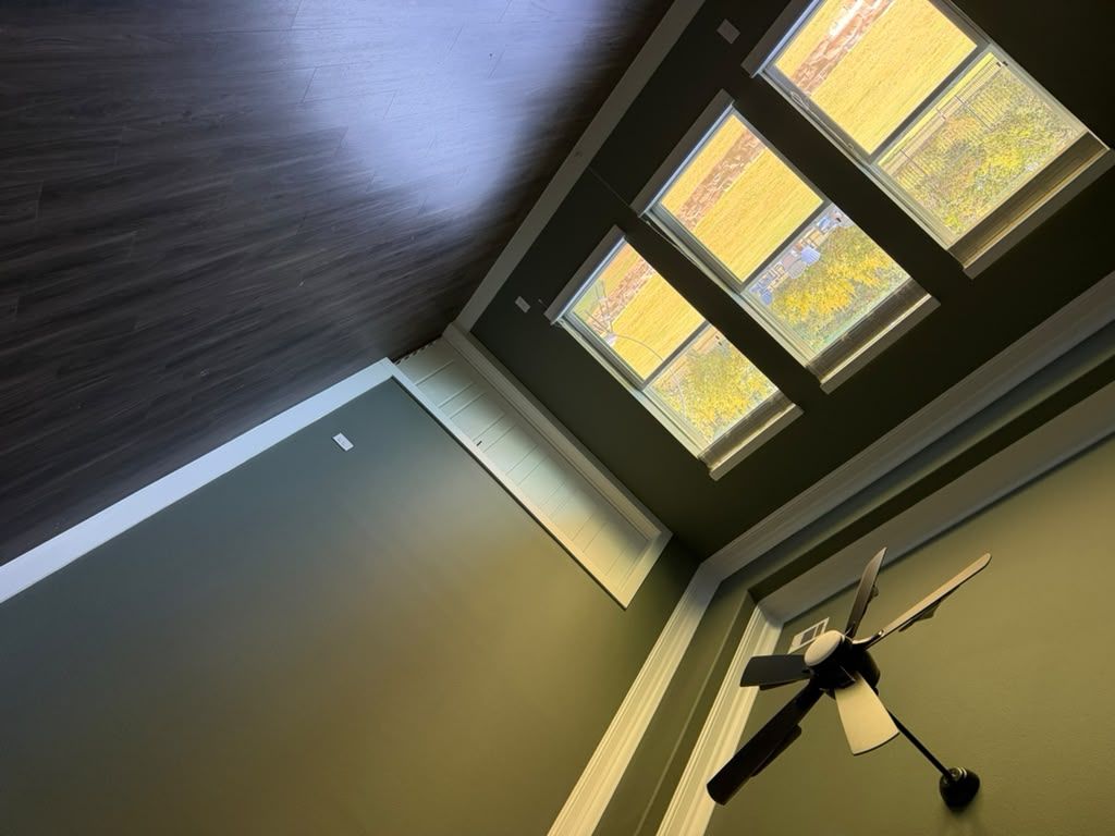 Ceiling fan and skylight windows in a room with dark wood trim, viewed at an angle