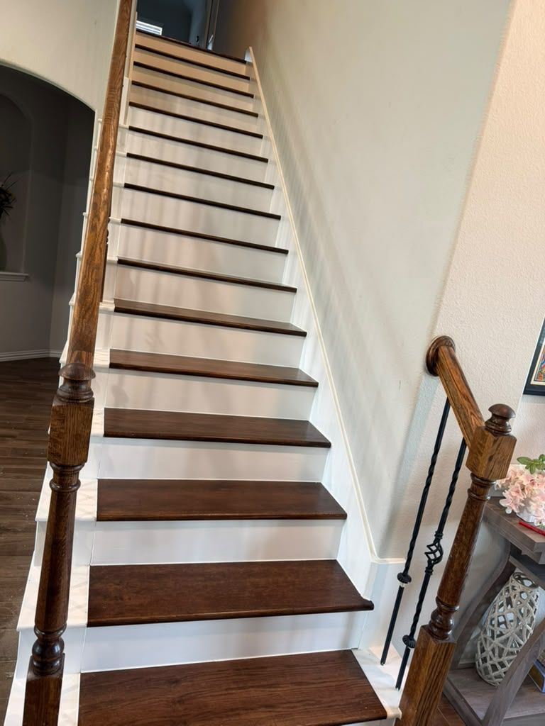Steep indoor staircase with dark wood treads, white risers, and metal railings beside a hallway