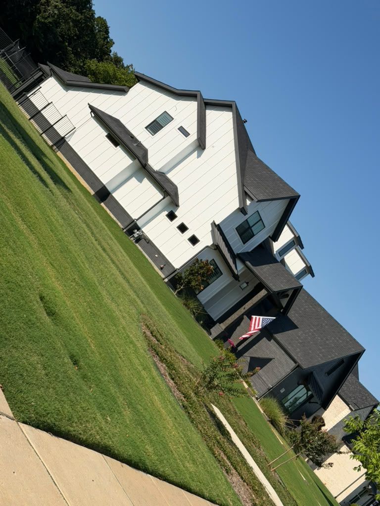 Suburban houses on a slanted street with green lawns and a cloudy sky, viewed at a diagonal angle