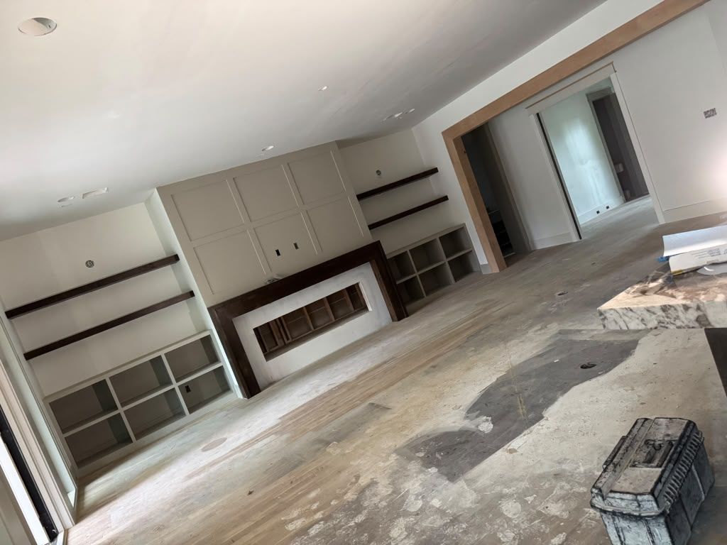 Unfinished living room with built-in shelving, fireplace, and construction debris on the floor
