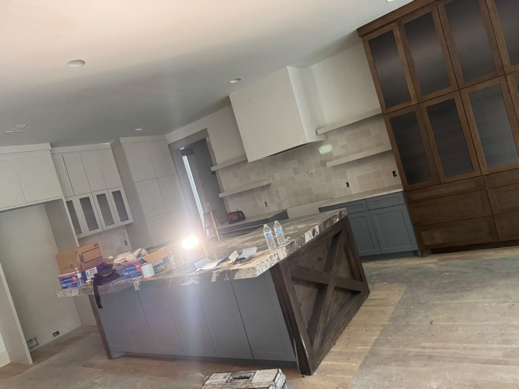 Modern kitchen with an island, light cabinets, and a large dark wood pantry wall.