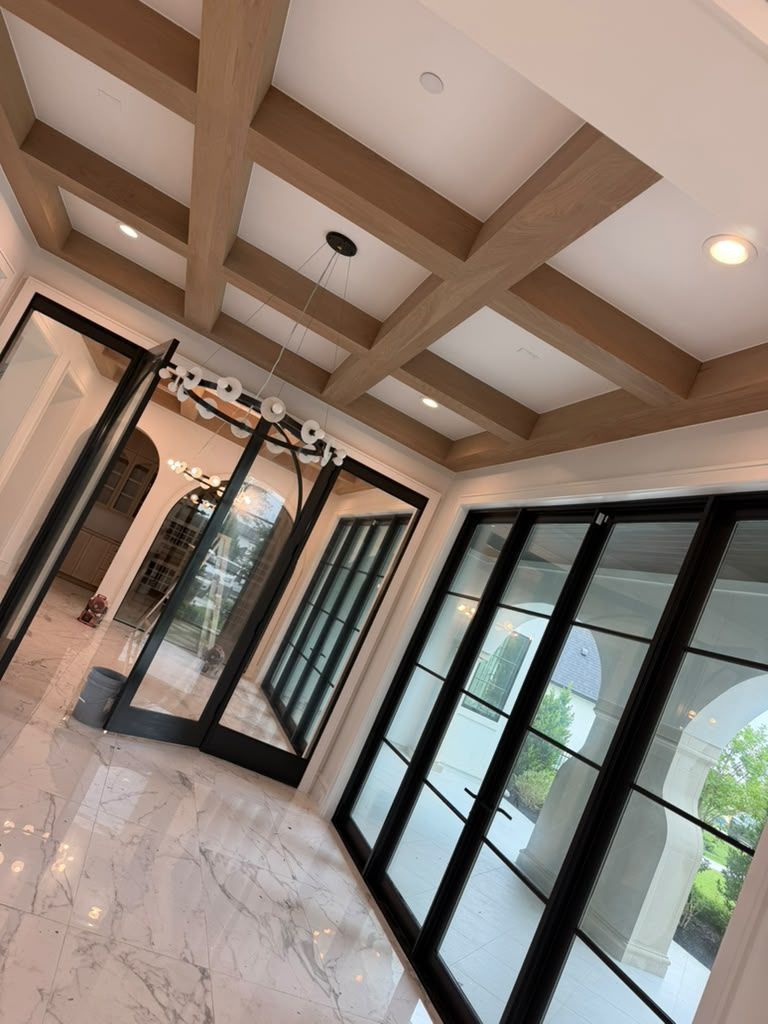 Bright lobby with glass doors, marble floor, and wood-beamed ceiling.