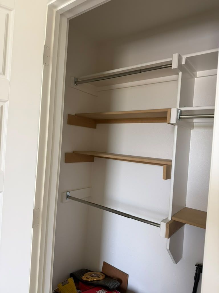 Open closet with wire shelves, wooden shelves, and a box of clothes on the floor