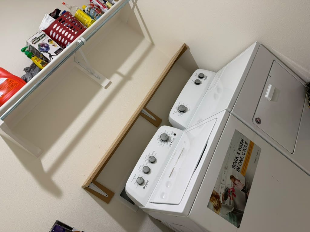 Laundry room with a washer and dryer beside shelves holding cleaning supplies.