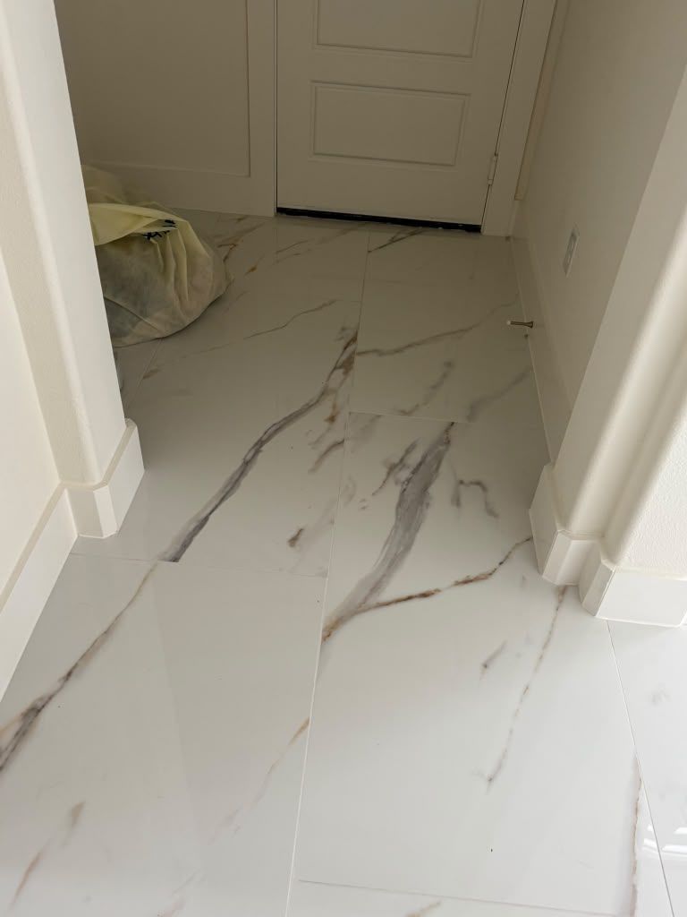 White marble-look tiled hallway floor with gray veining leading to a closed door