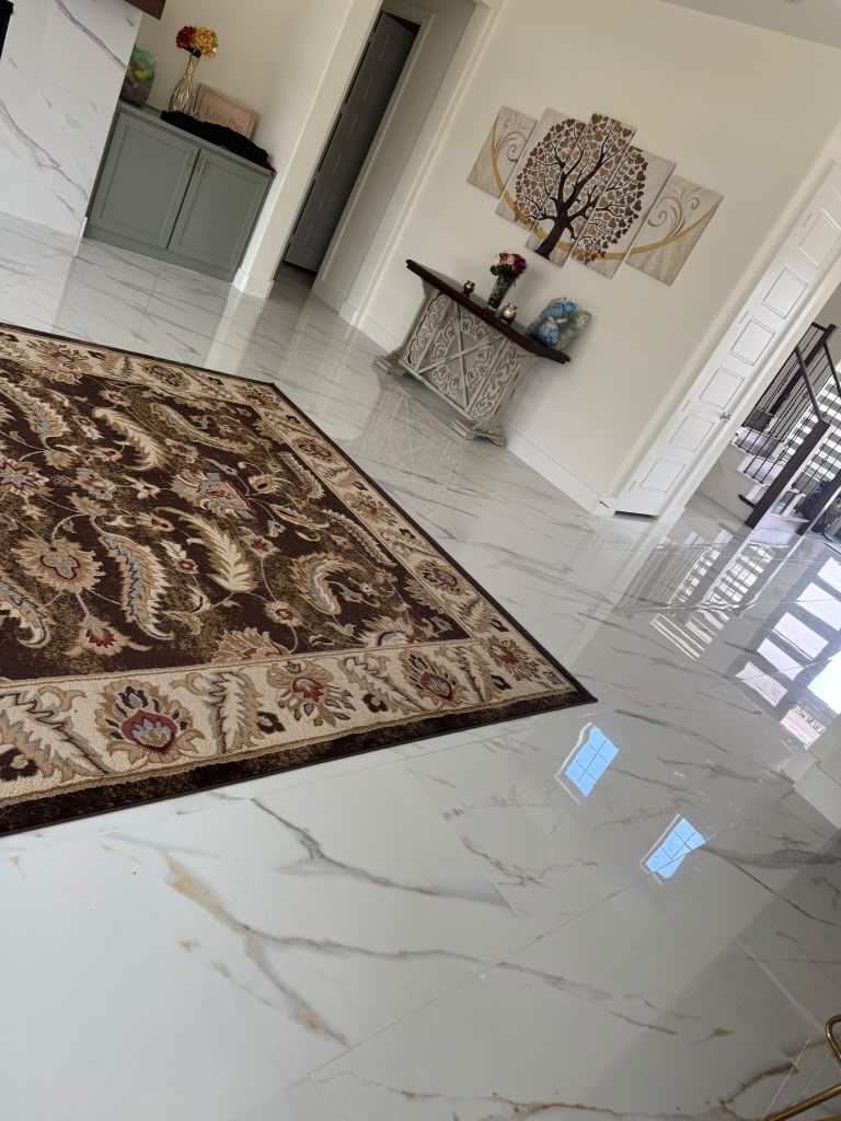 Modern living room with glossy white floor, patterned rug, wall art, and decorative console table