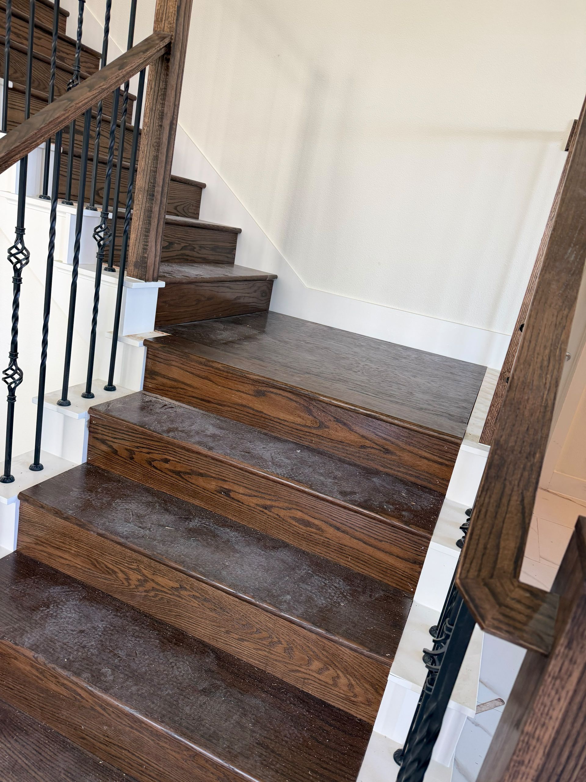 Wooden staircase with dark railing and beige walls indoors