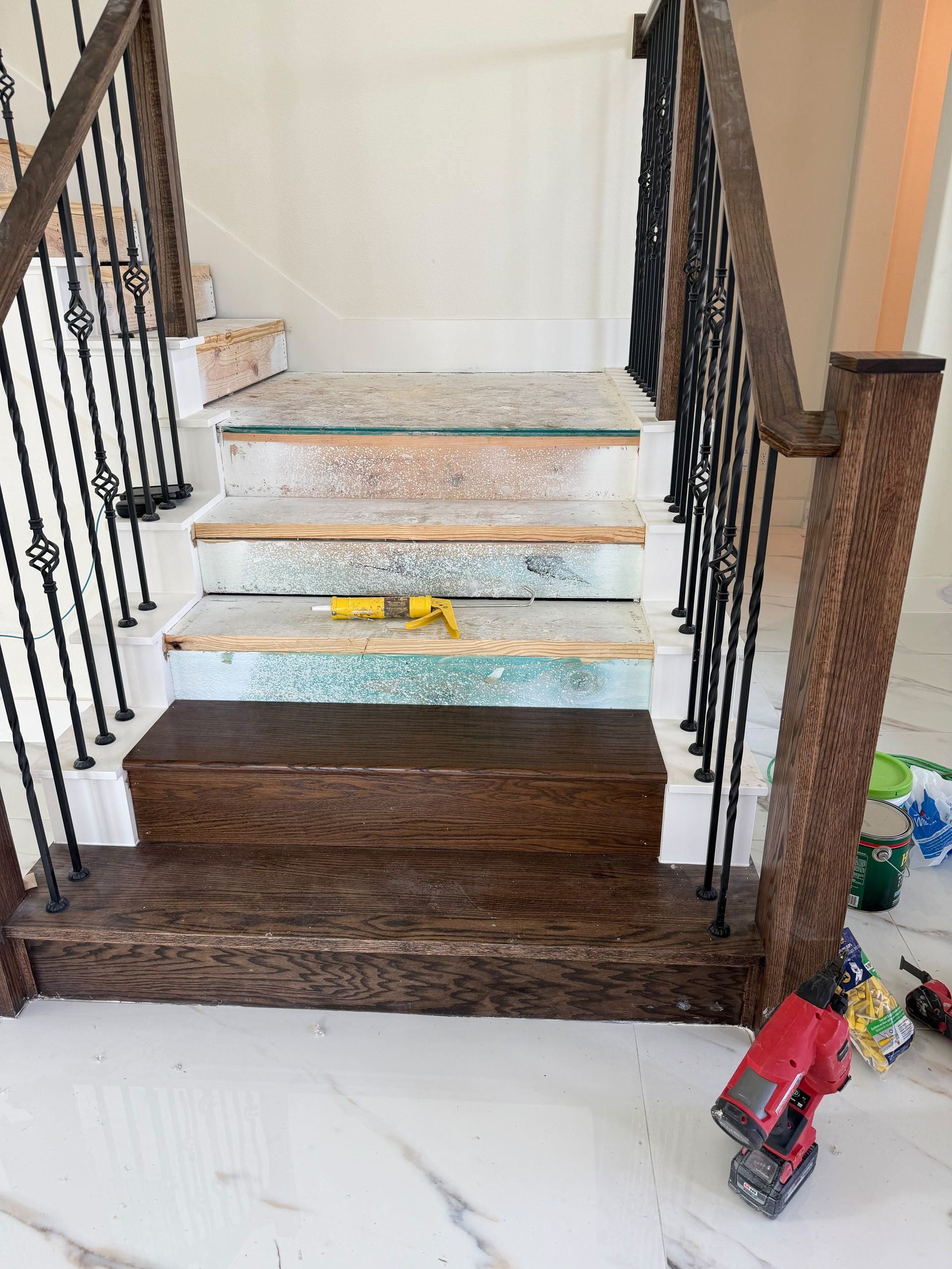 Indoor staircase with painted wooden steps, black railings, and toys at the base