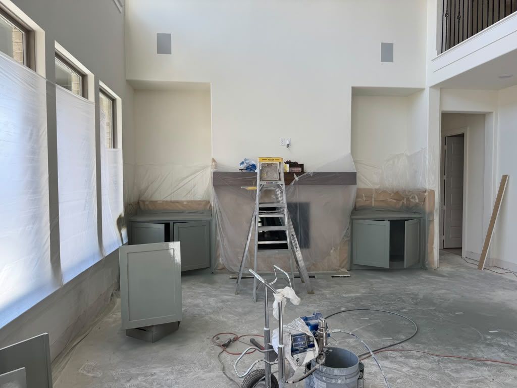 Renovation site with ladders, tools, and cabinets in a bright room with high ceilings