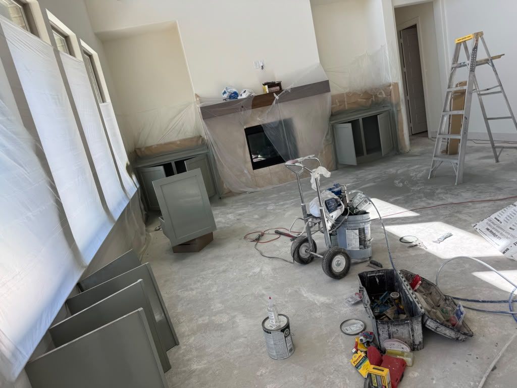 Renovation site with fireplace, ladder, tools, and cabinets on a dusty floor